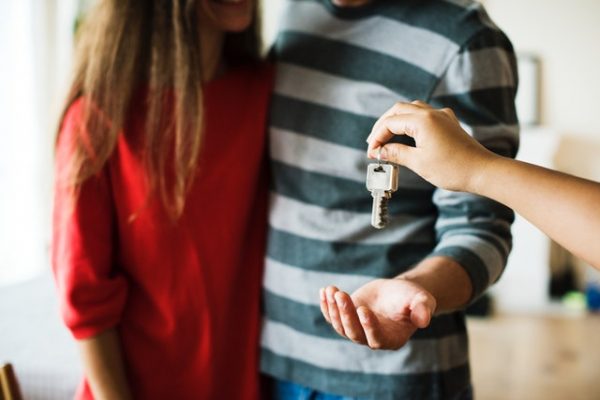 Hand giving the keys to a property to two adolescents