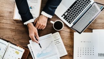 top down view on desk of businessman with coffee, laptop and paper