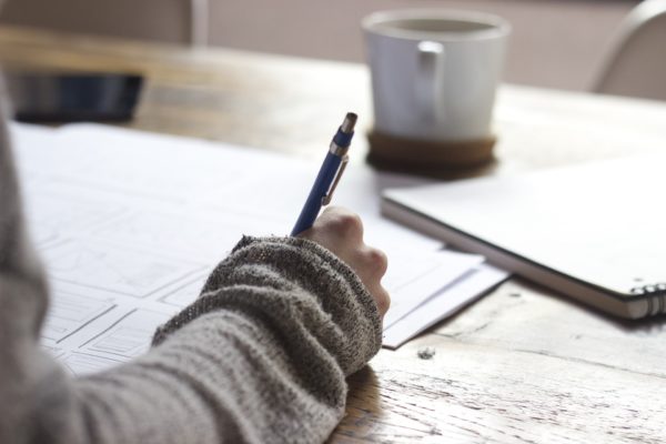 Hand writing on paper with coffee besides