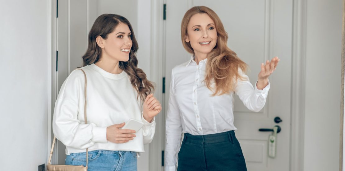 1 woman real estate agent shows house to another woman